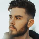 Mann im Freien mit dunklem Haar und einem Taper Fade Haarschnitt mit texturiertem Deckhaar
