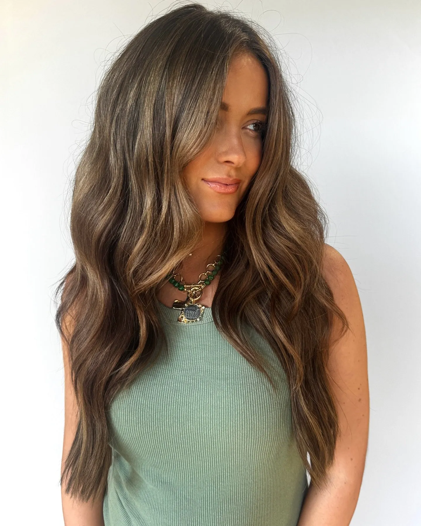 Lange, gewellte brünette Haare mit sanften, sonnengeküssten französischen Highlights, die sich auf die Längen und Spitzen konzentrieren
