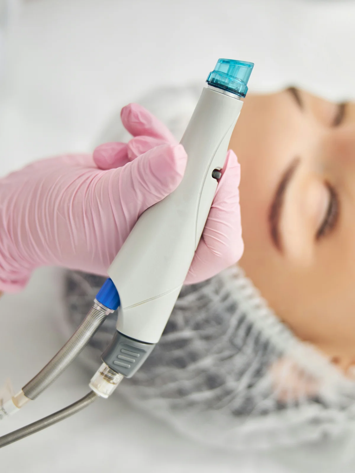 Nahaufnahme eines HydraFacial-Geräts mit Spiralaufsatz in der Hand einer Kosmetikerin
