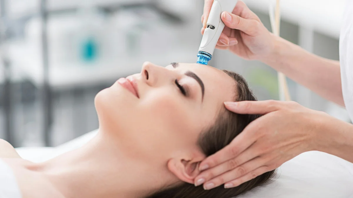 Nahaufnahme einer entspannten Frau mit geschlossenen Augen während einer HydraFacial-Behandlung in einem ruhigen Salon