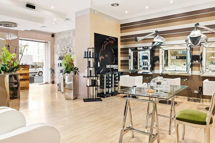 Elegante Styling-Plätze im Hair Queen in Cagliari mit cremefarben-braun gestreiften Wänden und grossen silbernen Pflanzgefässen.