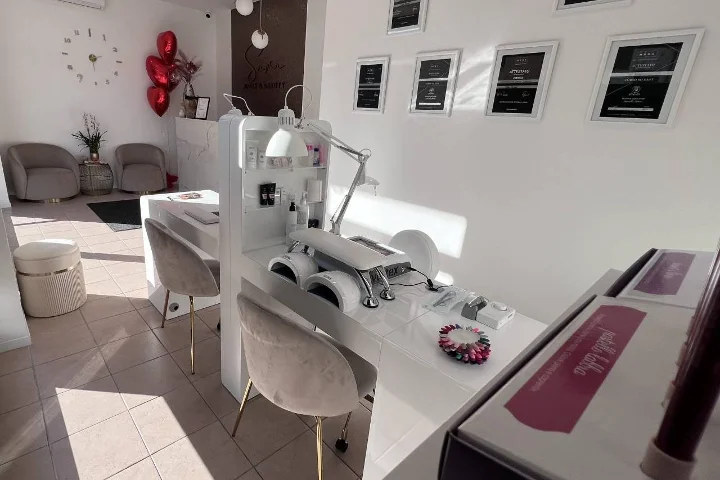 Weisses Nagelstudio Sara Nails&Beauty in Tortolì mit grauen Samtstühlen und gerahmten Zertifikaten an der Wand.