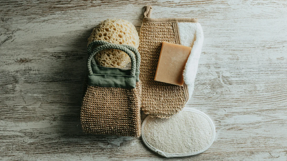Flatlay mit Peeling-Handschuhen, einem Naturschwamm und einer Peelingseife
